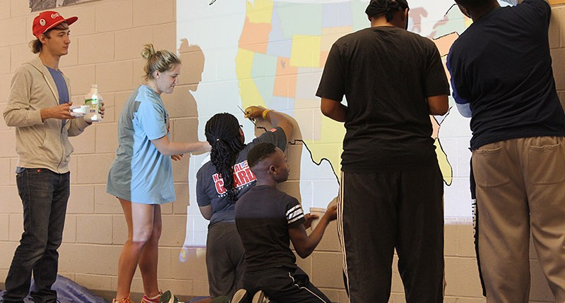 During an alternative spring break, student volunteers paint maps at West Tallahatchie High School.